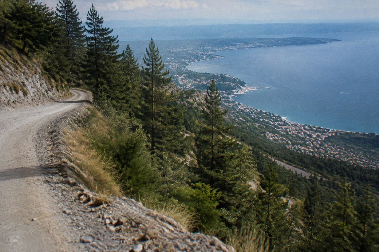 Open 4x4 shuttle vehicle climbing the dusty hairpin road up Mount Vesuvius with the Bay of Naples below