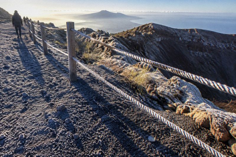 Cold December morning over the Vesuvius crater rim with low sun, frost on the gravel and long shadows