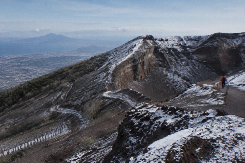 Vesuvius cone with a light dusting of snow on the crater rim under a cold blue sky, bare vines below
