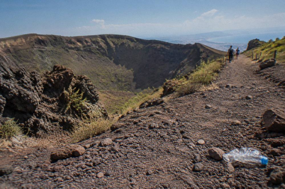 Dry volcanic gravel path climbing toward the Vesuvius crater rim with loose stones underfoot