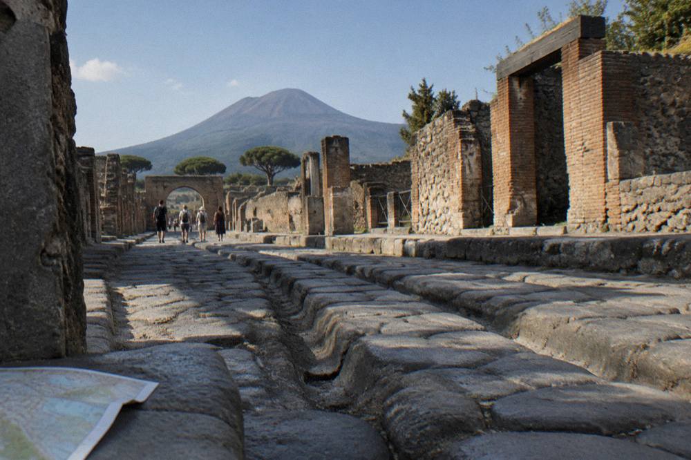 Stone-paved ancient street in Pompeii with worn cart ruts and ruined walls