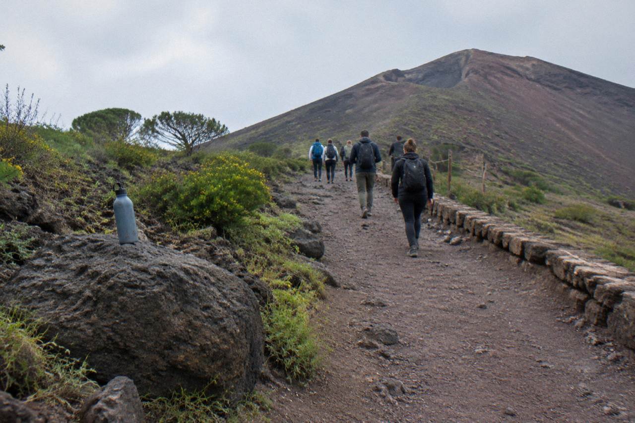 Guided walking group on a stone path above the Bay of Naples near Vesuvius