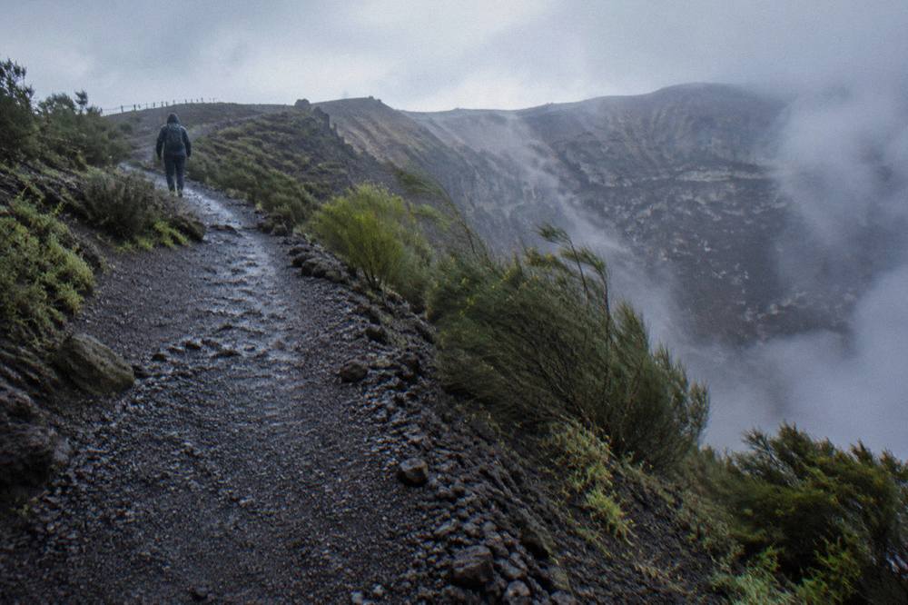 Volcanic gravel path climbing toward the Vesuvius crater rim with scattered scrub