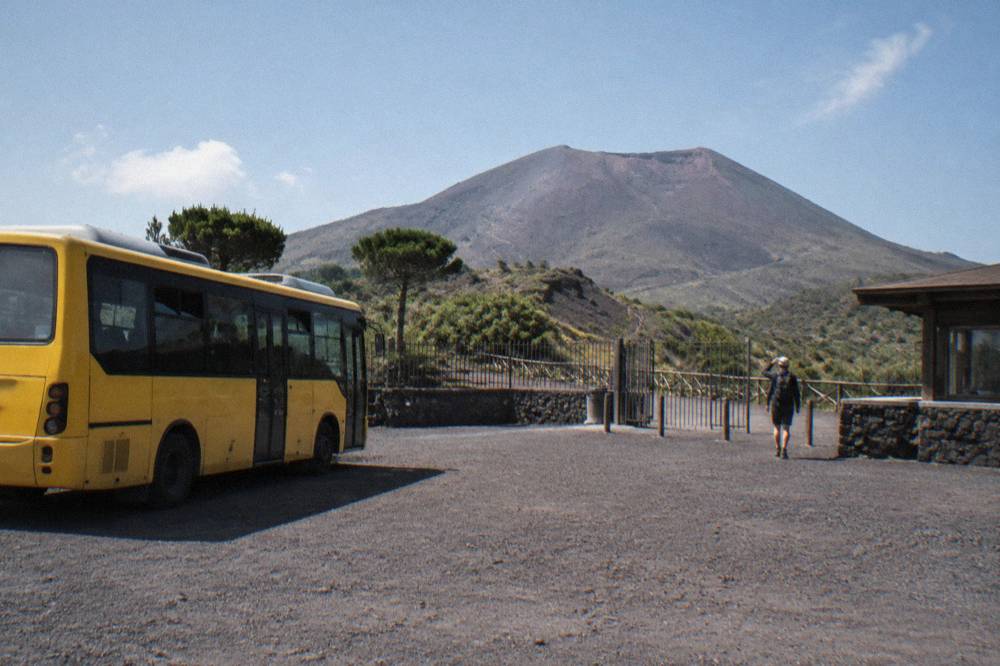 Yellow public bus parked at a sheltered stop on the slopes of Mount Vesuvius