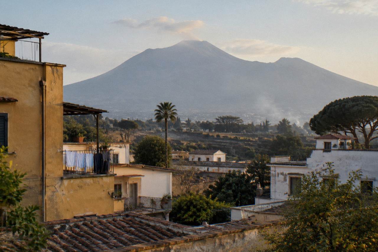 View across rooftops of modern Pompei toward the slopes of Mount Vesuvius under a clear sky