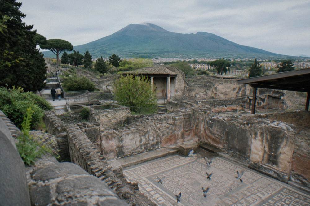 The excavated stone walls of Herculaneum with the Vesuvius slope rising behind them