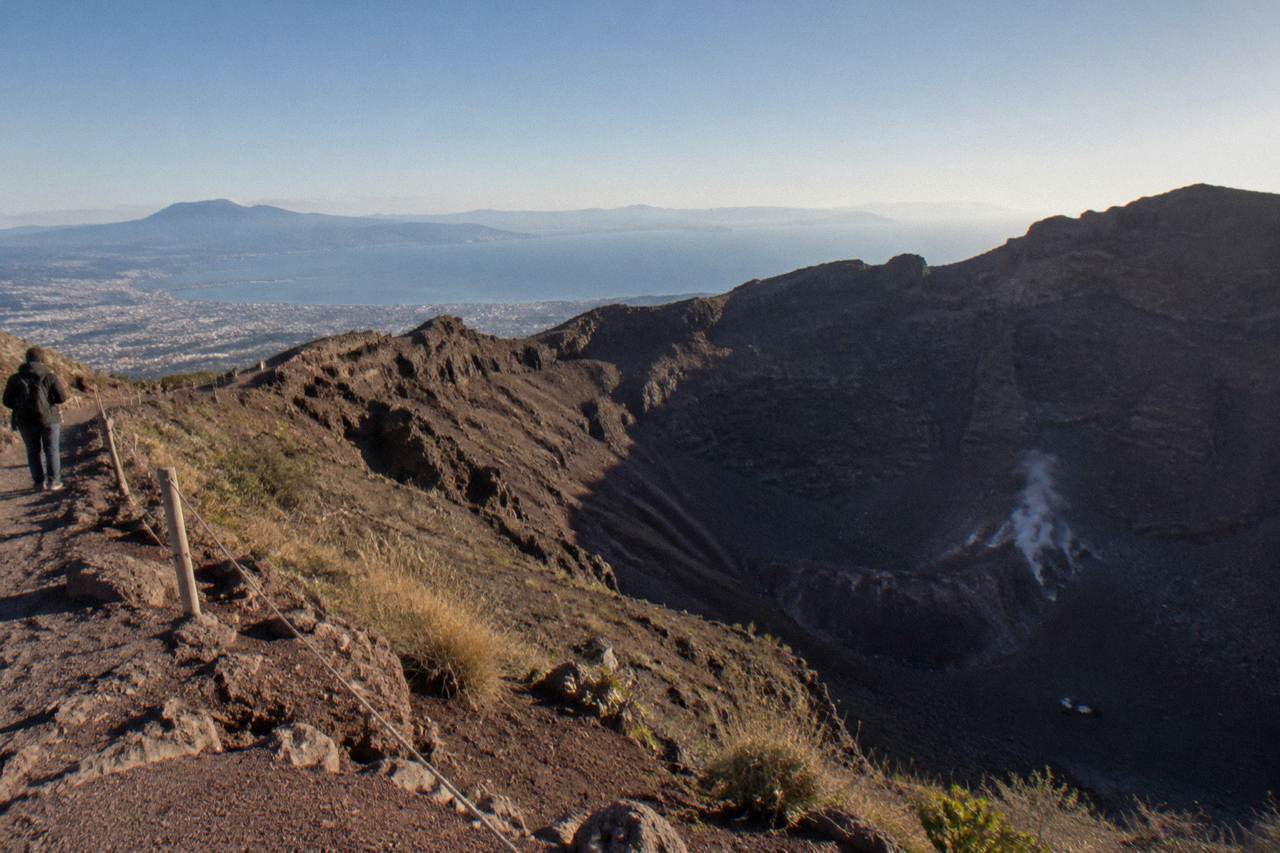 The Vesuvius crater rim under a clear sky with the Bay of Naples in the distance