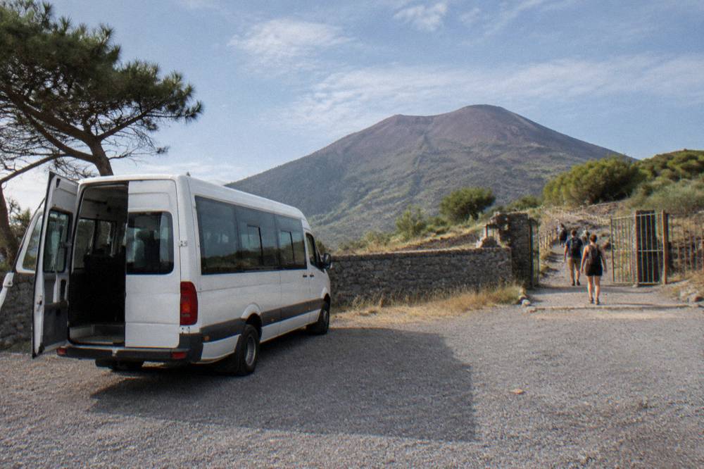 A shuttle minibus parked at the Quota 1000 trailhead plaza below the crater path