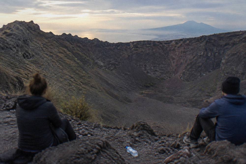 Hikers resting on rocks at the crater viewpoint looking across the wide elliptical crater