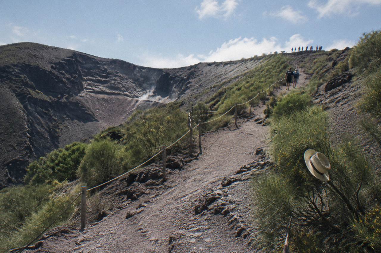 A winding dirt footpath climbing through scrub toward the Vesuvius crater rim under a clear sky