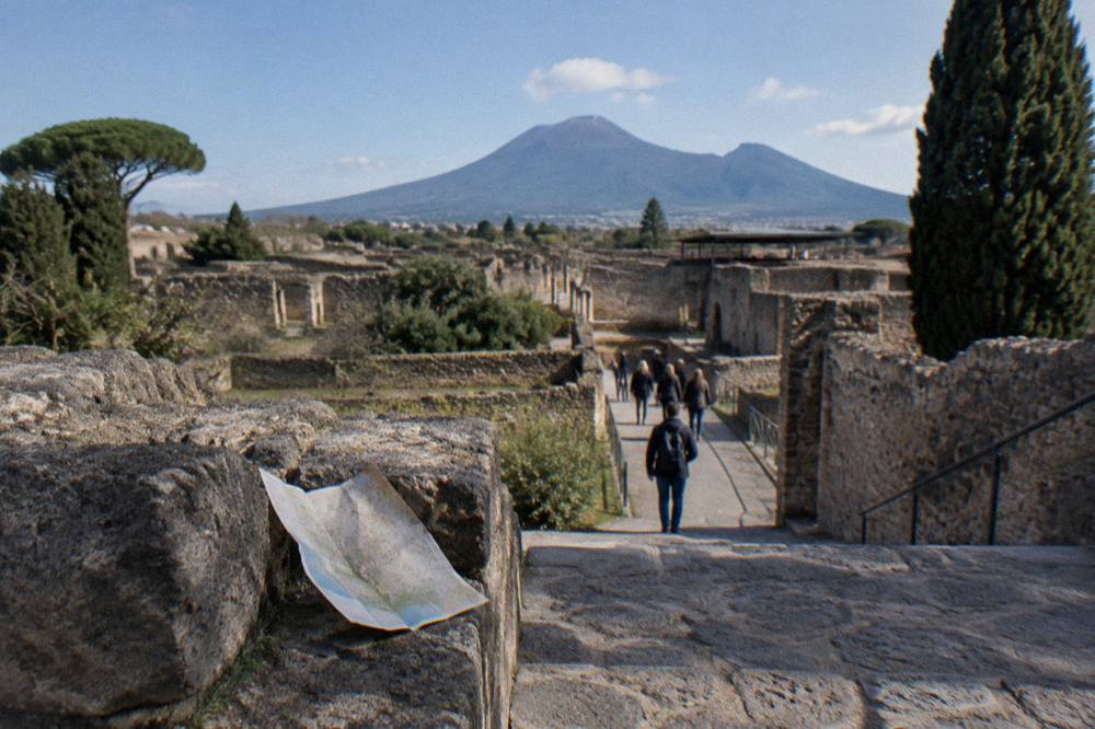 Stone ruins of Pompeii with Vesuvius rising in the background under a clear sky