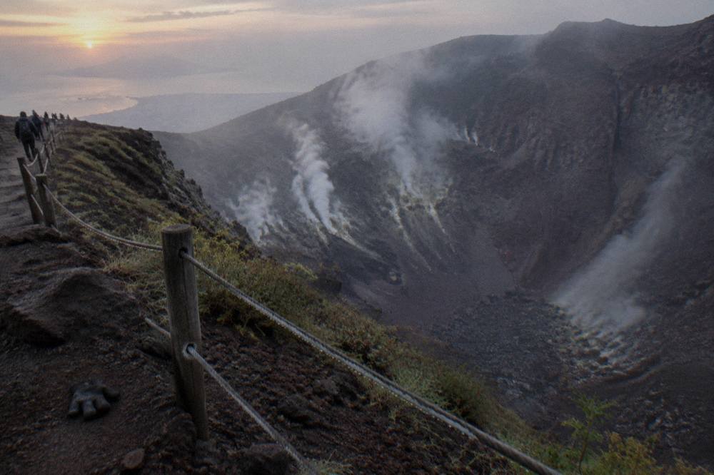 The crater rim of Mount Vesuvius with steam rising from fumaroles on the inner walls.