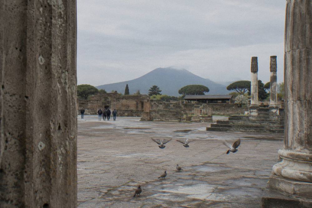 Weathered stone columns of the Pompeii Forum with the volcano in the distance