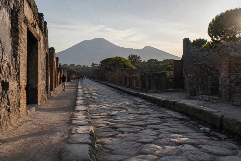 Empty ancient paved street at Pompeii lined with stone walls in late afternoon light
