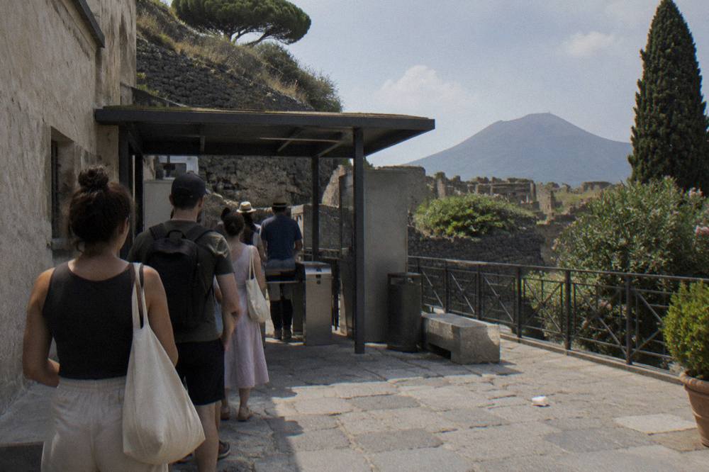 Ticket queue at an archaeological park entrance with visitors waiting at a gate