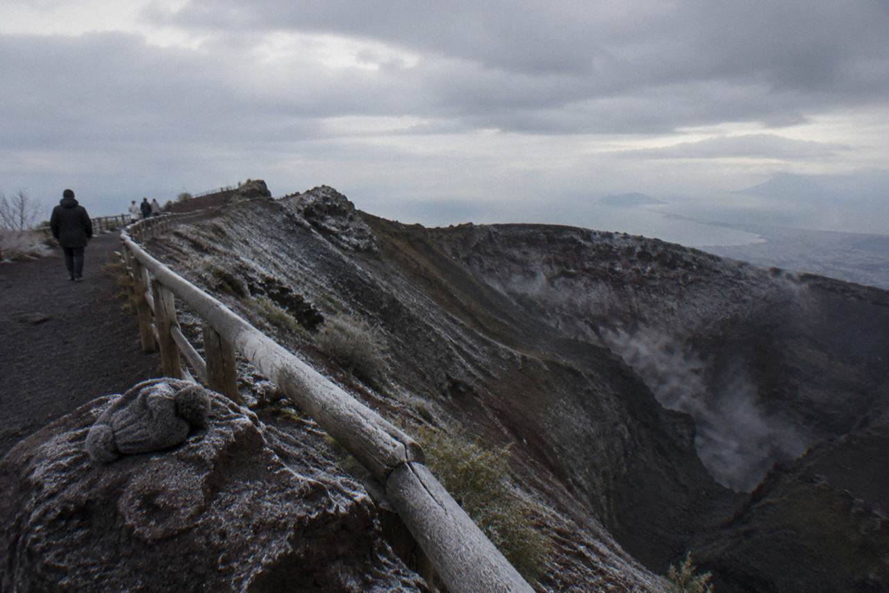 The Vesuvius crater rim under a grey sky with volcanic rock slopes below