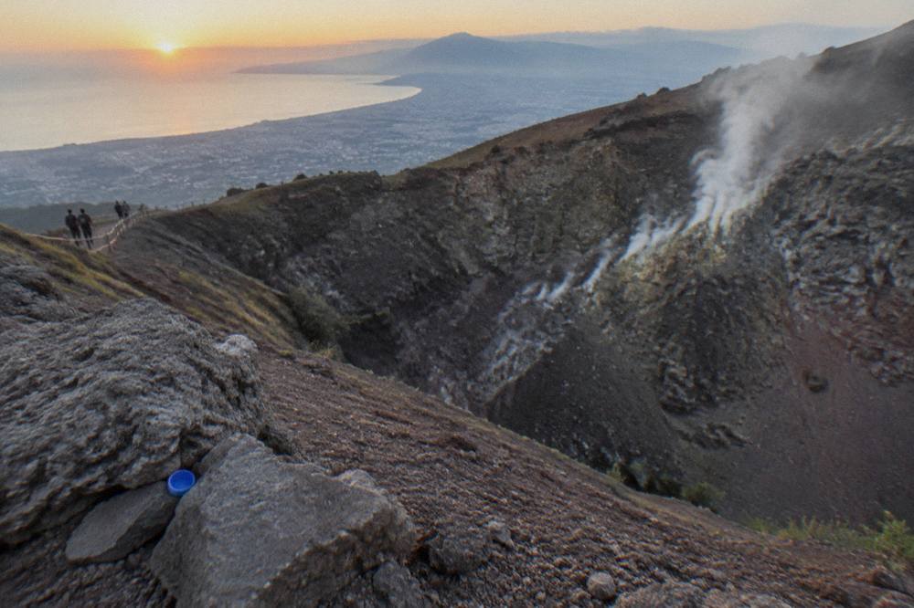 The wide elliptical crater of Vesuvius with steam rising from the inner walls