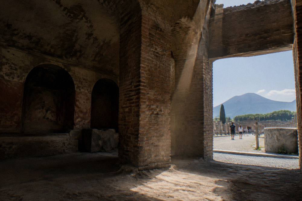 Weathered stone columns and plaster casts of Pompeii victims inside an excavated ruin building
