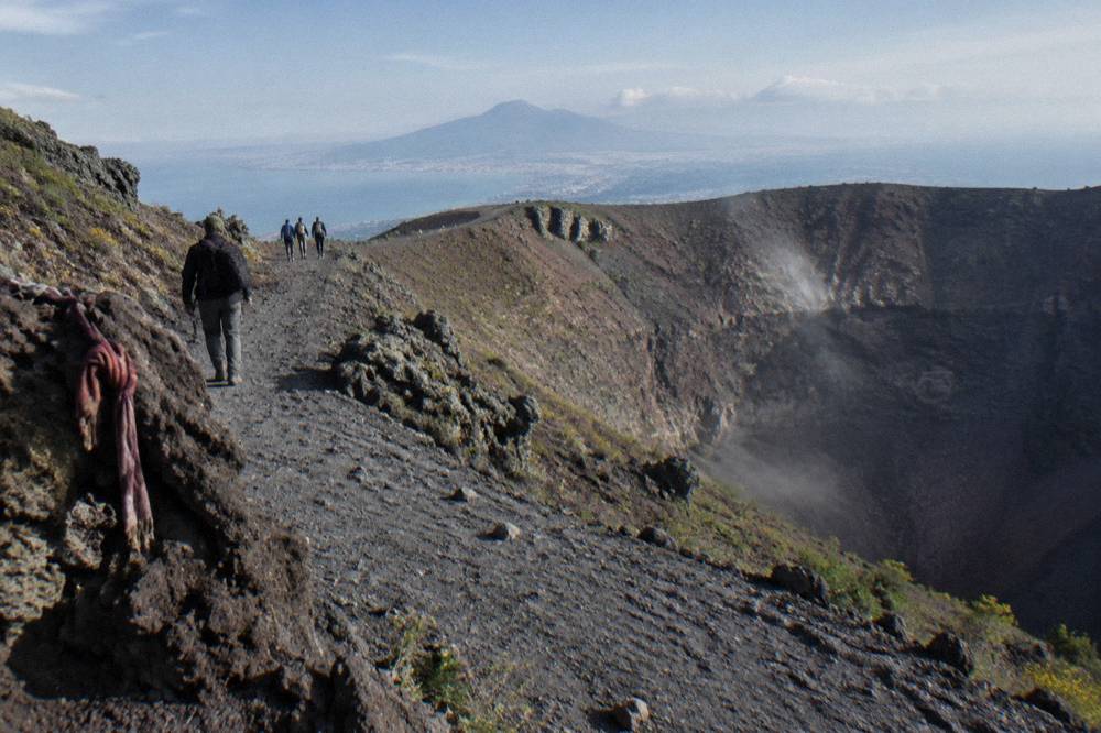 Volcanological guide leading a small group along the crater trail of Mount Vesuvius toward the rim
