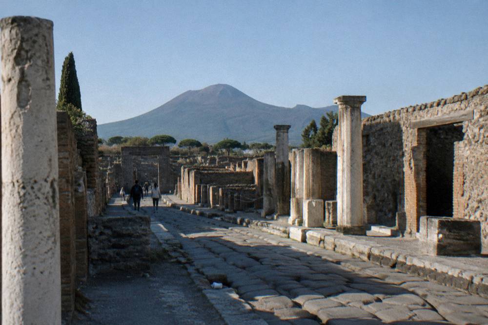 The stone streets of the ancient city with the volcano rising in the distance under a clear sky