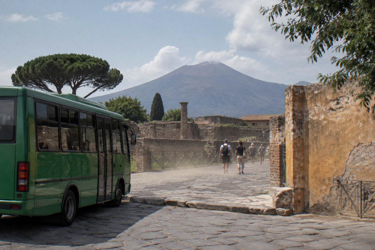 A shuttle bus parked on the road below the volcanic cone of Vesuvius
