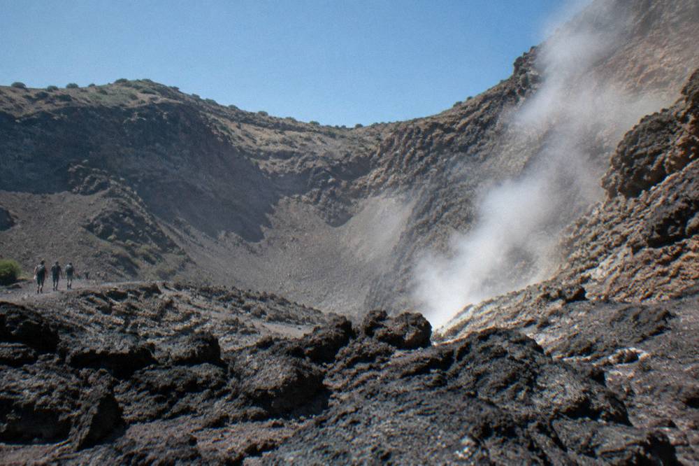 Steam rising from fumaroles inside the crater of Mount Vesuvius against a bright sky