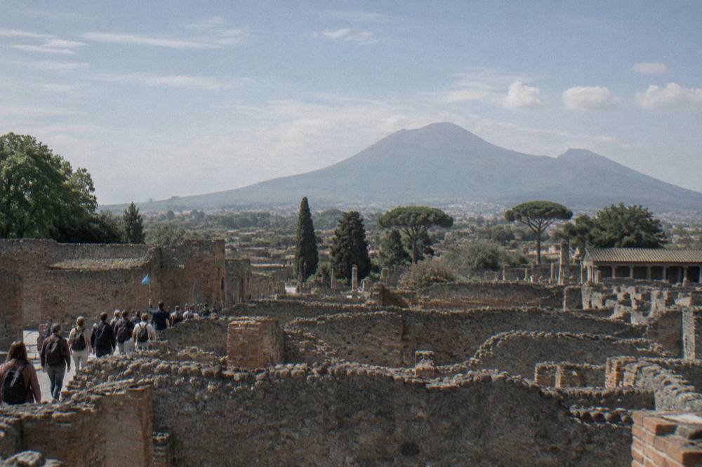 Wide view across the Pompeii excavations toward Mount Vesuvius under afternoon light