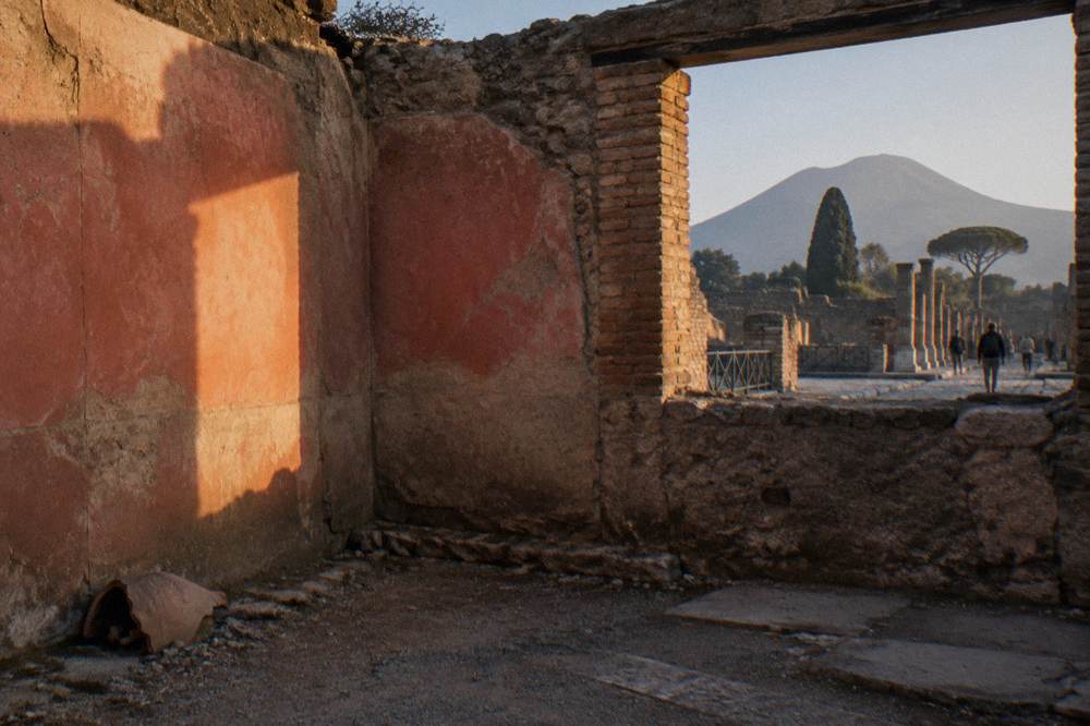 Roman columns and stone walls of a Pompeii building interior with warm daylight on the ancient masonry