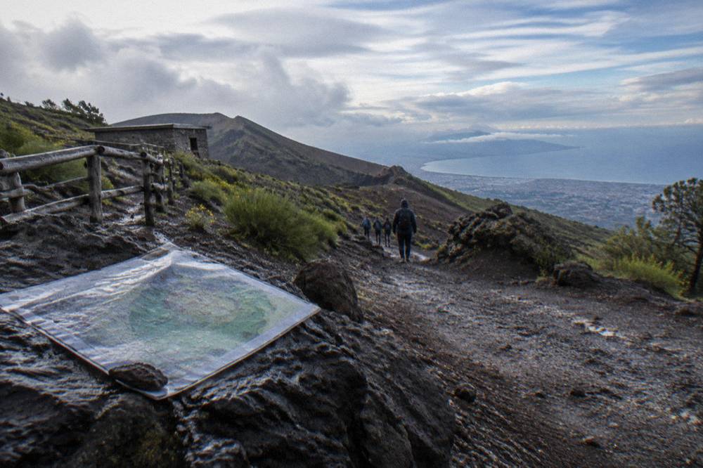 The Vesuvius crater rim under a wide sky with dark volcanic rock slopes below