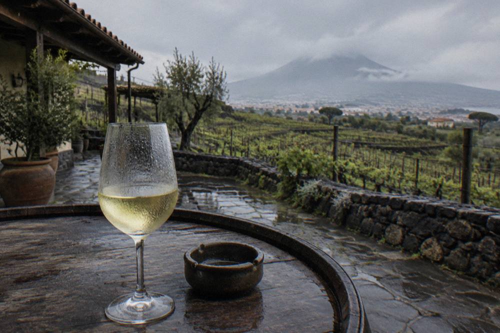 A glass of white wine on a wooden table overlooking terraced vineyards