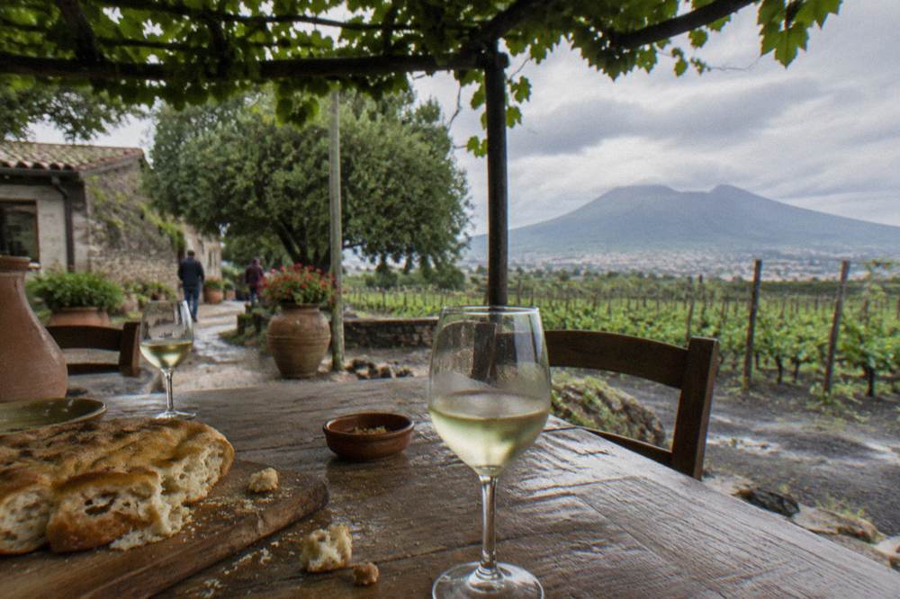 A rustic lunch table with wine glasses, bread and local dishes under a pergola