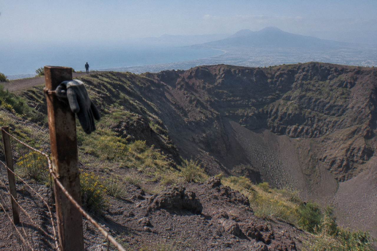 The wide crater of Mount Vesuvius under a clear sky above the Bay of Naples