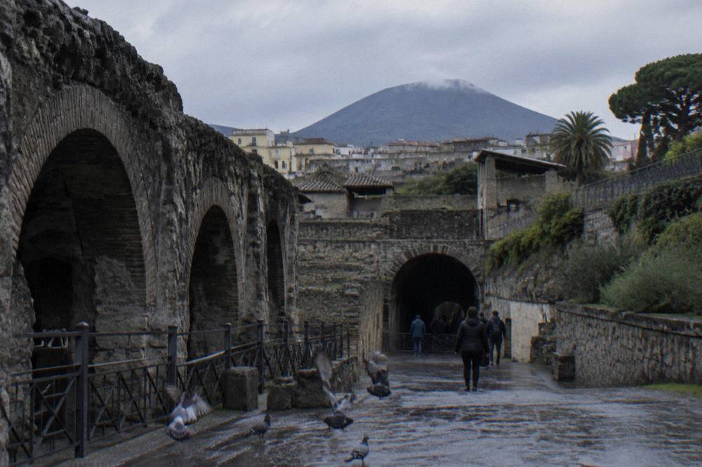 Ancient stone walls and arches of a buried Roman town with modern town rooftops beyond