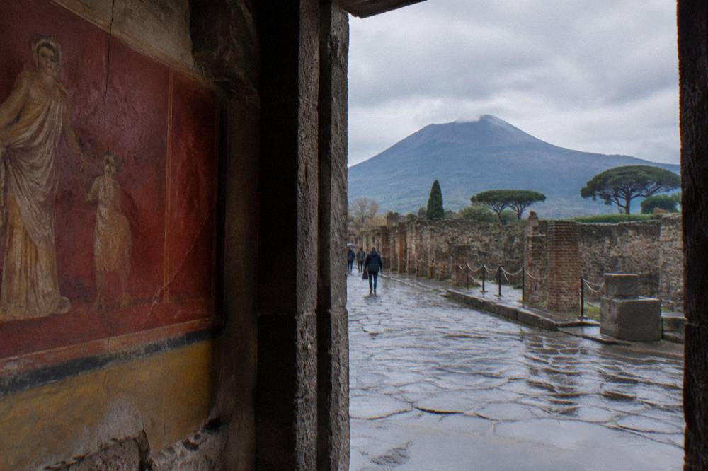 Close view of a well-preserved fresco on a Pompeii interior wall showing deep red and ochre pigments