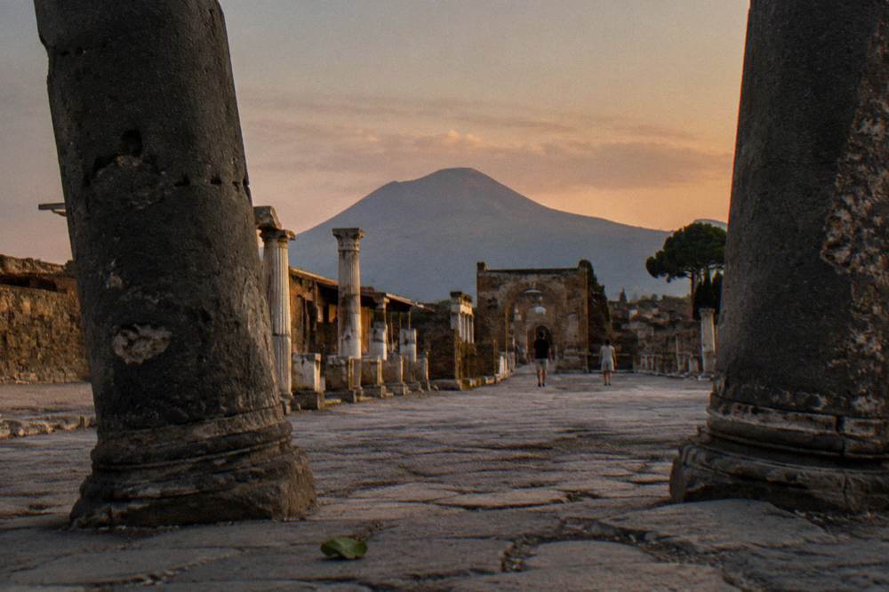 The stone columns of the Pompeii forum with Mount Vesuvius rising in the background