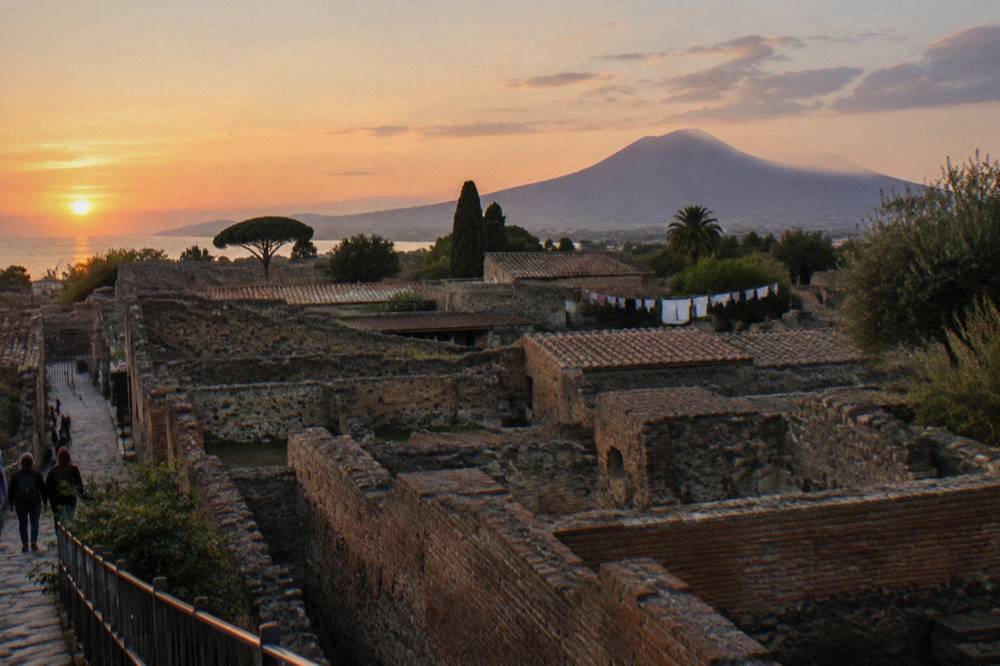 A wide view over the excavated rooftops and walls of Pompeii toward the distant volcano cone