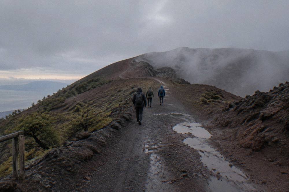 Hikers on the wide ash path toward the Vesuvius crater rim in morning light