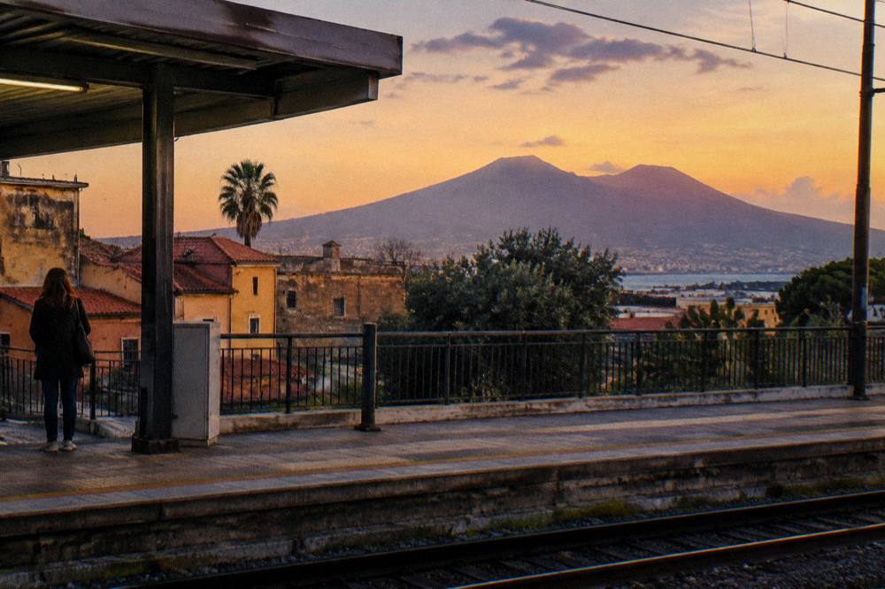An evening view over rooftops toward the Bay of Naples with the volcanic silhouette on the horizon