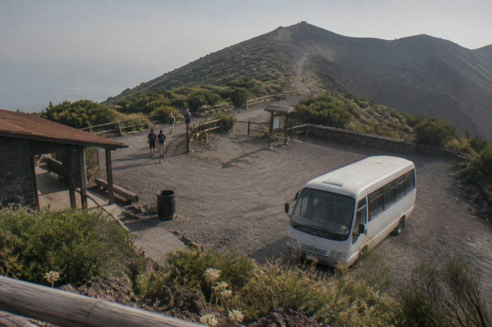 A shuttle minibus parked at the Quota 1000 trailhead plaza below the Vesuvius crater path