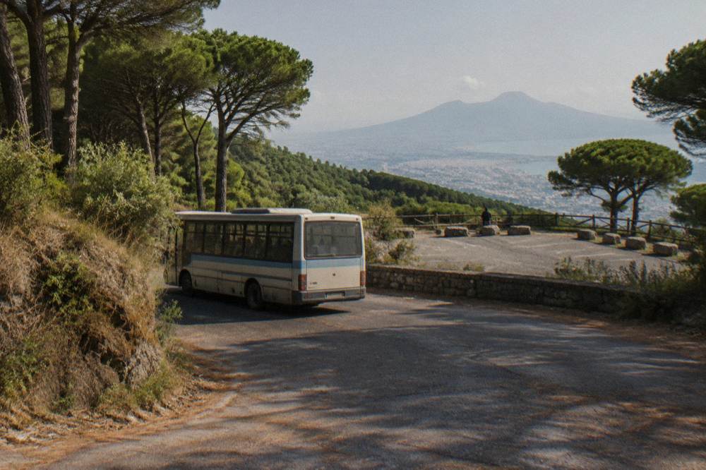 A public bus on the wooded switchback road below the Vesuvius trailhead