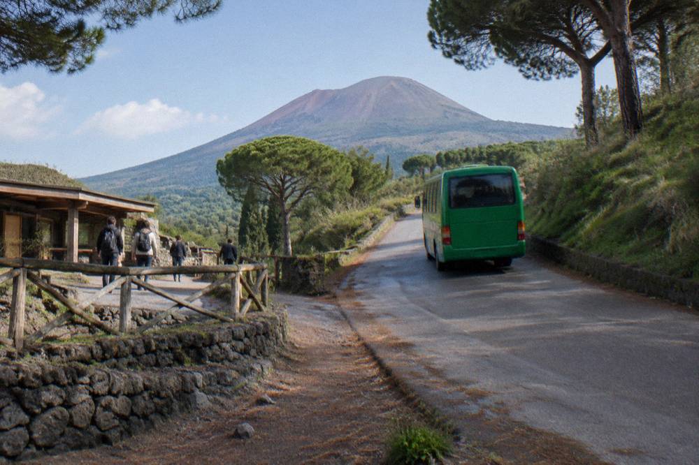 A regional bus on the road climbing through pine woods toward the Vesuvius trailhead