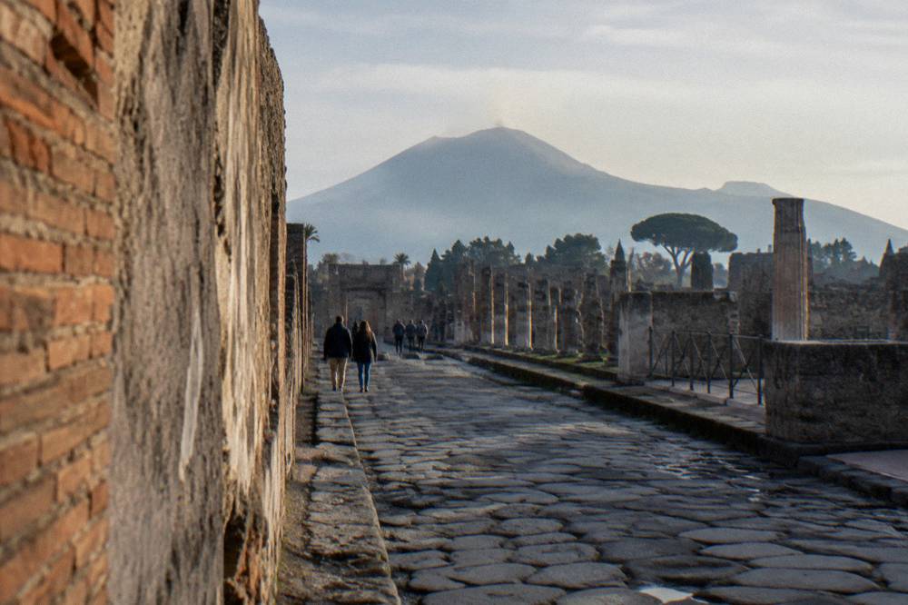 Stone streets of Pompeii with the profile of Mount Vesuvius rising behind the ruins