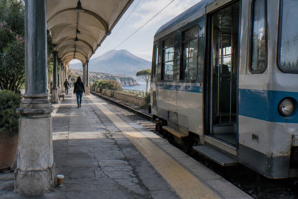 A single carriage regional train at a small southern Italian station platform in morning light
