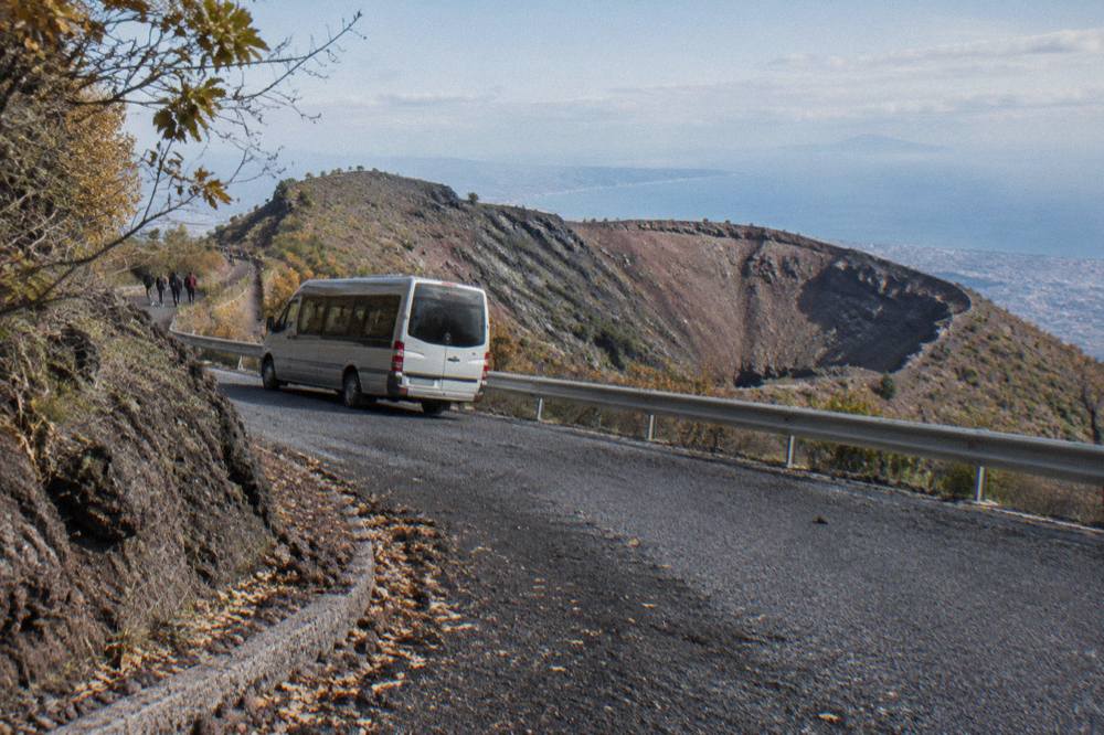A bus climbing a switchback road on the wooded slopes of Vesuvius