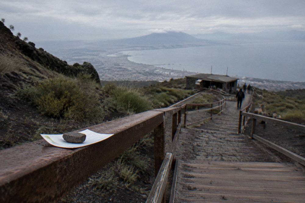 Scanned entry ticket held toward a small hut on the crater path with the bay in the distance