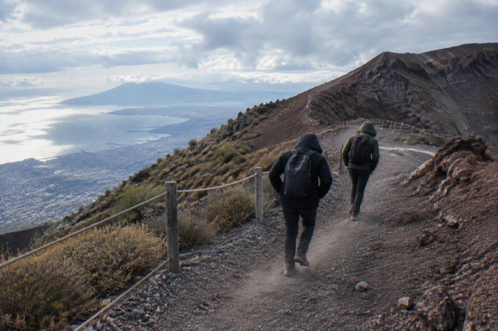 Hikers on a gravel switchback path below the crater rim of Vesuvius