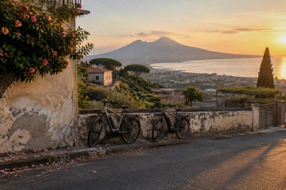 Electric bicycles parked on a road overlooking the Bay of Naples toward Vesuvius