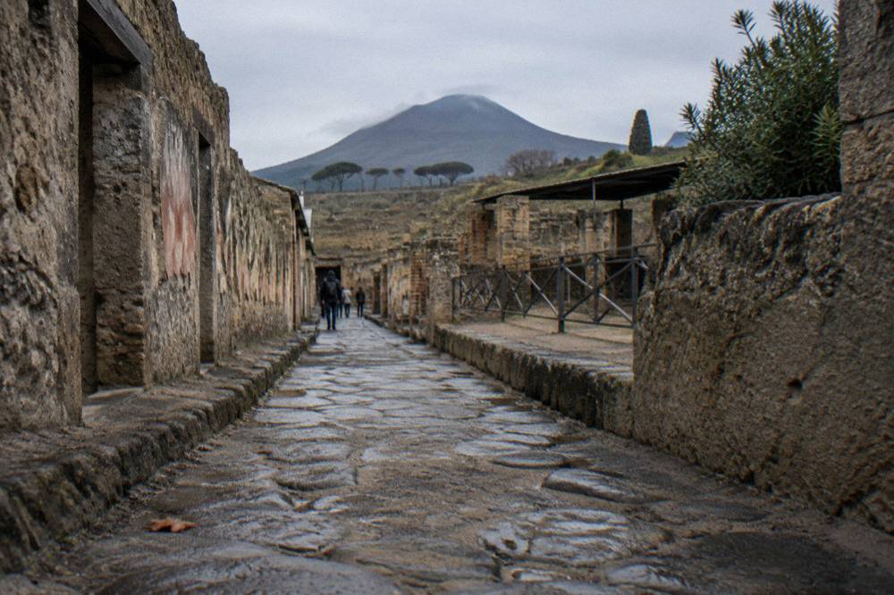 An excavated ancient street of stone paving with ruined walls of a buried Roman town.
