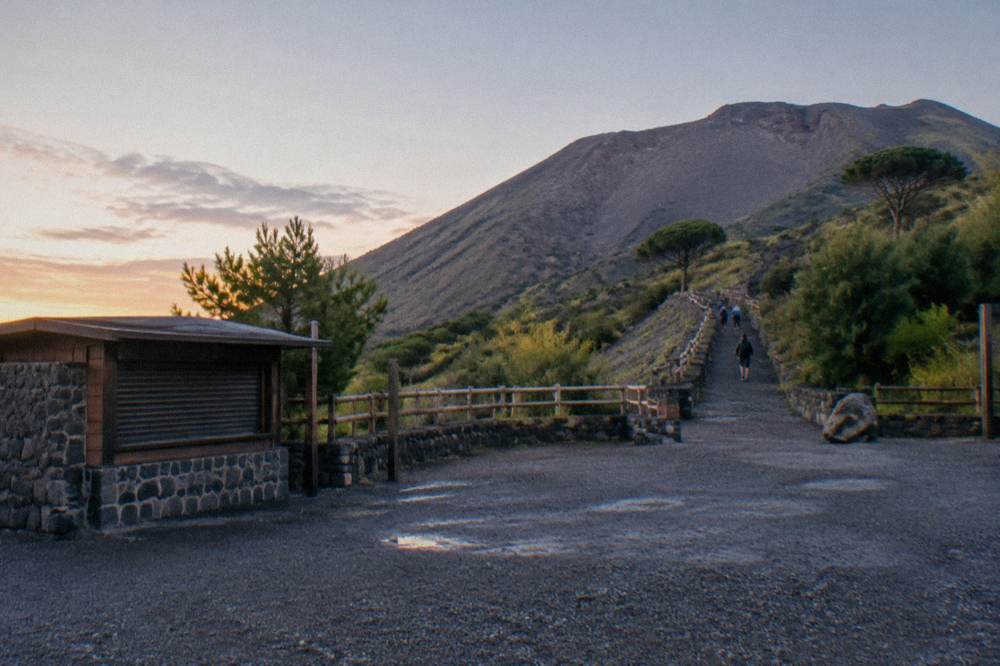 A stone trail rising over dark ash slopes toward the crater rim of Vesuvius.