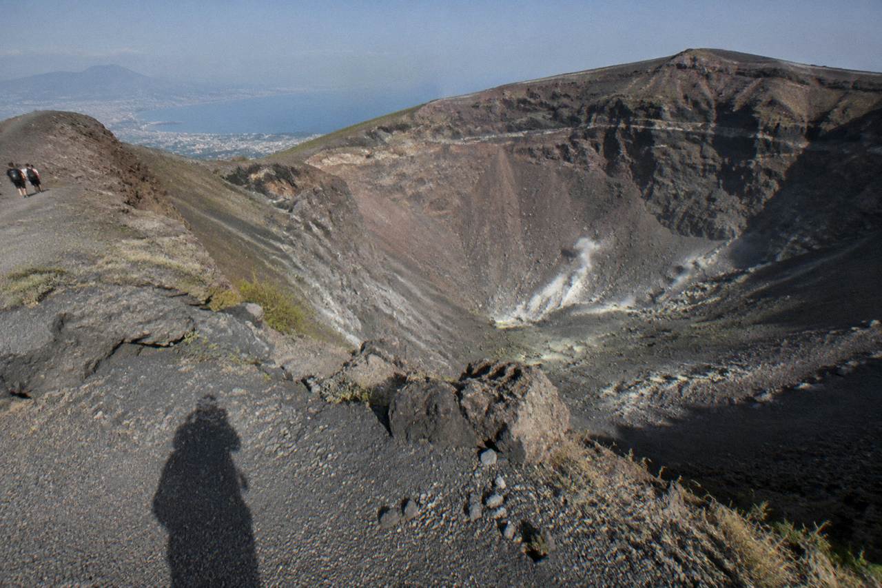 Wide volcanic crater rim with layered ash slopes under an open sky